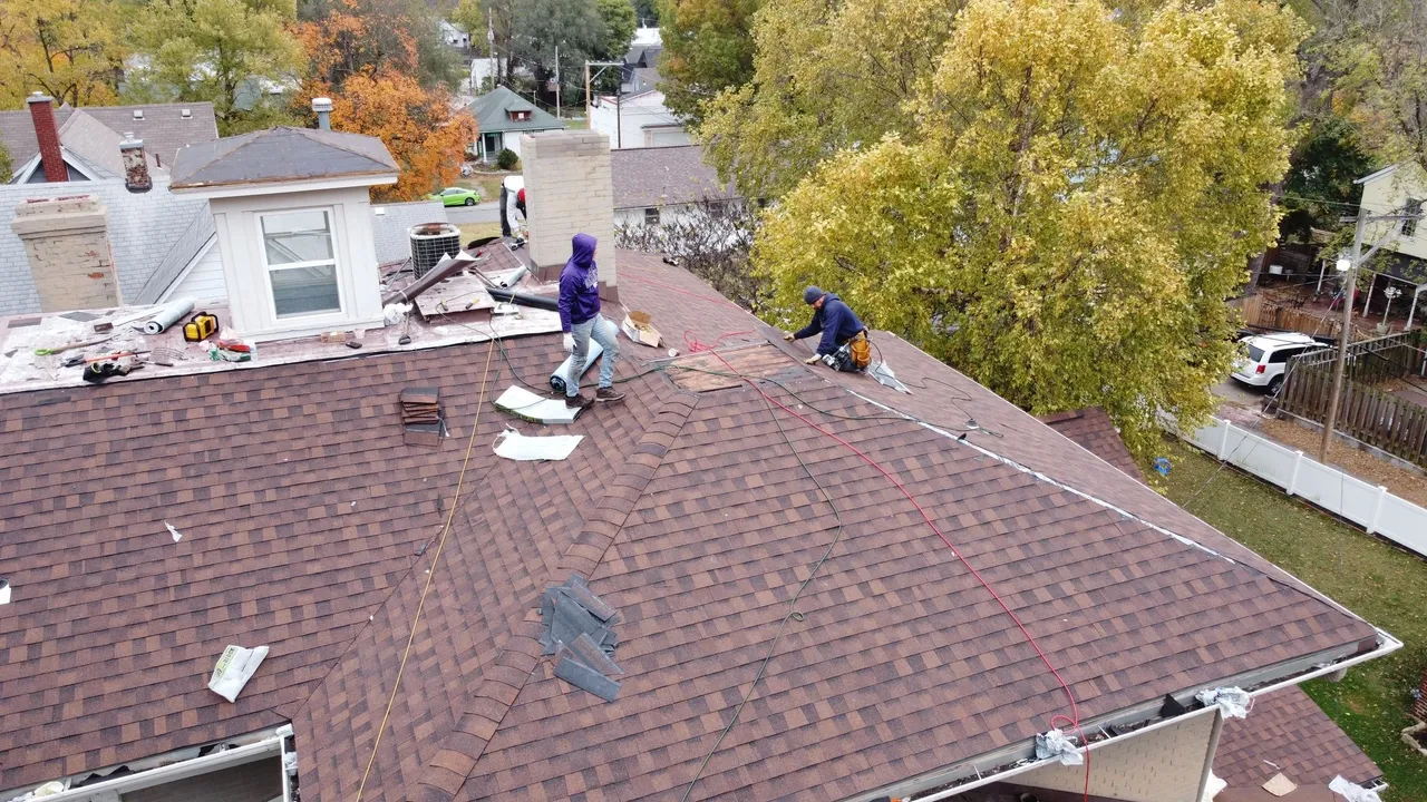 Two men working on a roof in the fall.